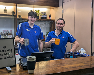 two baristas holding milk jugs and smiling